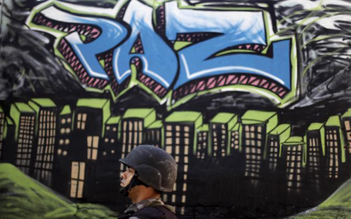 Un soldato di guardia sotto un murales in una favela di Rio